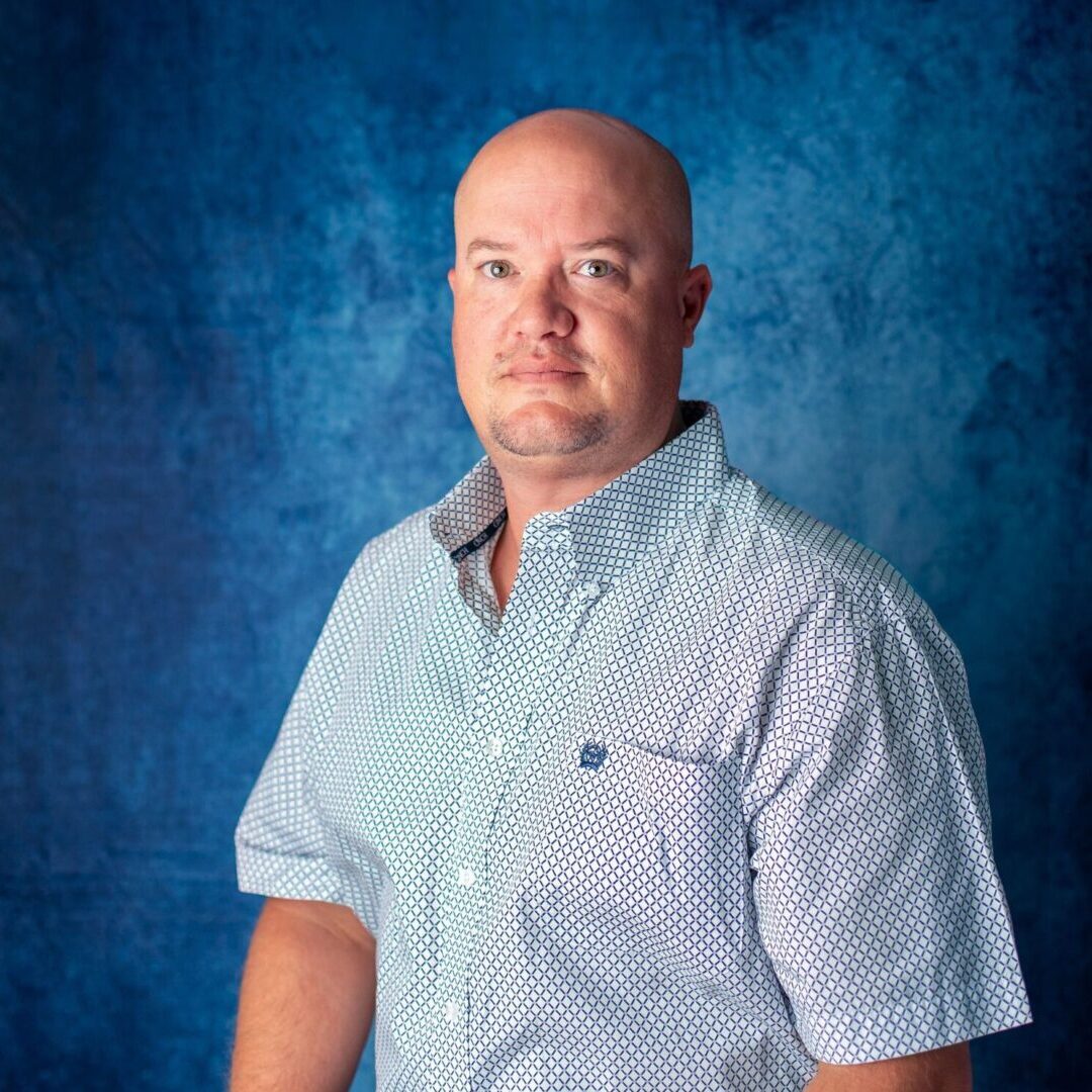 A man standing in front of a blue background.